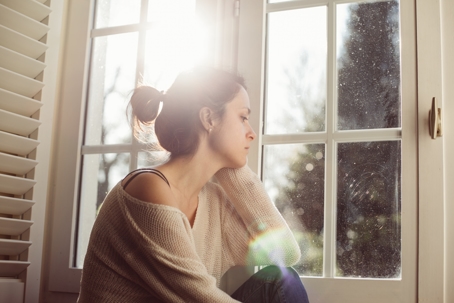 Unhappy housewife sitting near the window stock photo